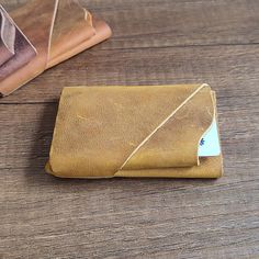 a brown leather wallet sitting on top of a wooden table next to two folded books