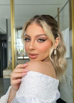 a woman with blonde hair and blue eyes wearing a white dress in front of a mirror