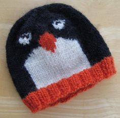 a knitted penguin hat sitting on top of a wooden table