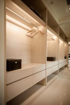 an empty walk - in closet with white cabinets and drawers is lit by recessed lighting