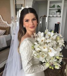 a woman in a wedding dress holding a bouquet of white flowers and wearing a veil