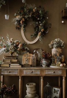 a wooden table topped with lots of flowers and books next to a wall mounted wreath