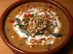 a brown bowl filled with soup on top of a wooden table