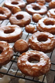 several glazed donuts are cooling on a rack