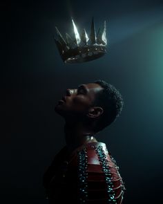 a man with a crown on his head looking up at the light coming from behind him