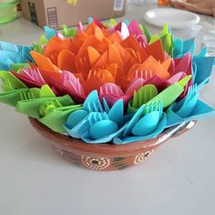 a bowl filled with colorful paper flowers on top of a table