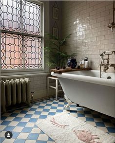 a bath tub sitting next to a window in a room with blue and white tiles