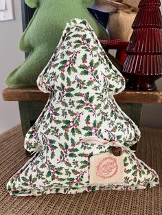 two stuffed animals sitting next to each other on a wooden bench near a christmas tree