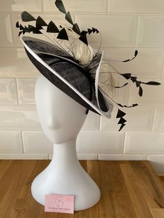 Make a statement with this elegant Black Sinamay Flower Fascinator.  It features a striking white trim detailing and beautiful feather designs, perfect for adding a touch of sophistication to any ensemble.  Size dimensions: 30cm by 30cm. Fitted Black Fascinator With Feather Trim, Formal Fitted Mini Hat With Feather Trim, Chic Fitted Fascinator With Feathers, Elegant Summer Fascinator With Ostrich Feathers, Formal Fitted Fascinator With Feather Trim, Chic Fitted Mini Hat With Feathers, Elegant Fitted Ostrich Feather Headpieces, White Feather Headpieces For Evening, White Feathered Headpieces For Evening