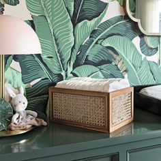 a baby crib in front of a green wall with palm leaves painted on it