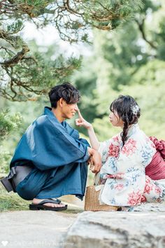 a man and woman sitting on the ground next to each other in kimonos