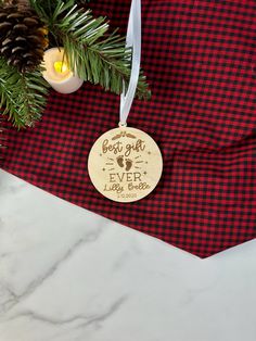 a wooden ornament hanging from a christmas tree on a red and black checkered table cloth