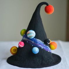 a black hat with colorful balls on it sitting on top of a white tablecloth