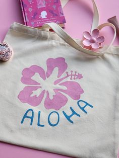 Hand-Painted Canvas Tote Bag - Hibiscus Flower & Aloha Design Bring a splash of tropical beauty and artistry to your everyday style with our hand-painted tote bag, featuring a vibrant Hibiscus flower and "Aloha" typography. Crafted from durable terylene cotton, this unique tote measures 41x40 cm (16x15.7 inches), offering plenty of space for all your essentials. Key Features: Original Design: Each tote bag features an exclusive, hand-painted Hibiscus flower and "Aloha" design, created with high- Tote Bag Painting Ideas Flowers, Tote Bag Design Painting, Cute Tote Bag Design Paint, Flower Tote Bag Design, Canvas Tote Bag Painting, Cute Tote Bag Design, Hibiscus Tote Bag, Painting Tote Bags, Painted Tote Bag