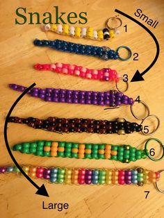 several beads are arranged in the shape of a snake on a wooden table with an arrow pointing to them