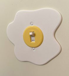 a yellow and white light switch sitting on top of a wall