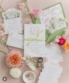 the wedding stationery is laid out with flowers and rings on it's side