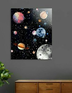 an image of planets in the sky on a wall above a dresser with a potted plant