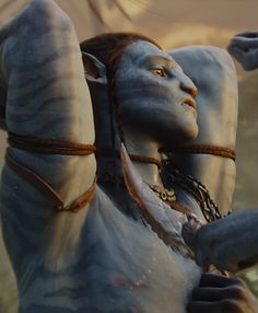 a woman dressed as avatar from avatar is holding her arm up in the air with both hands