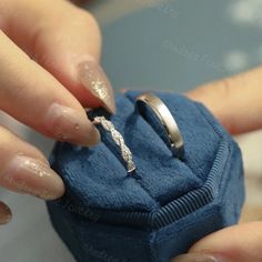 a woman is holding onto her wedding ring in a blue box with glitter on it