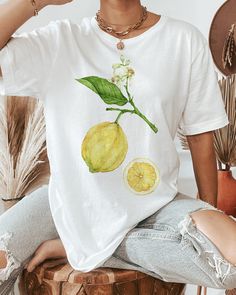 Refreshing summer t-shirt, featuring a Lemon plant, pictured with fruit, blossoms and a cross-section. Printed on a white t-shirt, made from durable lightweight cotton. Unisex fit - boxy and long. How it's made: * All prints are original watercolor designs hand-painted by a botanical artist. * Ethically made 100% cotton t-shirts that are made to last. * T-shirts are printed and shipped by my printing partner in the US, Canada, or Europe. * By buying from this shop you are directly supporting a woman-owned small business, created out of love for plants to educate, inspire and keep us connected to the natural world. About the artist: This Shop is an extension of my botanical illustration studio, where I create hand-painted watercolor art for international clients. Anna Farba Illustration is Lemon Shirt, Vegetable Plants, Fruit Shirt, Botanical Shirt, Graphic Inspiration, Fruit Print, Print Crop Tops, Art Shirts, Inspiration Mode