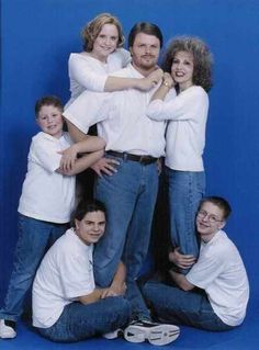 a family posing for a photo in front of a blue background with their arms around each other