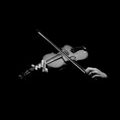 a black and white photo of a person holding a violin in the dark with their hands