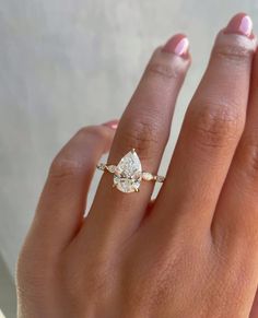 a woman's hand with a diamond ring on top of her finger and an engagement band