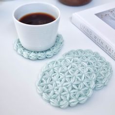 a cup of coffee sitting on top of a table next to a crocheted coaster