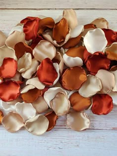 several different colors of fabric flowers on a white wooden surface