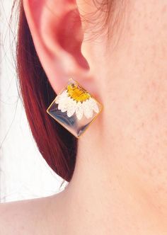 a close up of a person wearing a pair of earrings with flowers on it's ear