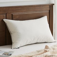 a white pillow sitting on top of a bed next to a brown wooden headboard