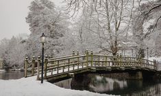 a snow covered bridge over a river next to a light pole and lampposts