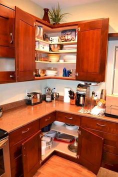 an open cabinet in the corner of a kitchen with stainless steel appliances and wooden cabinets