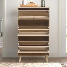 a tall wooden shelf with drawers in front of a door and a vase on top of it