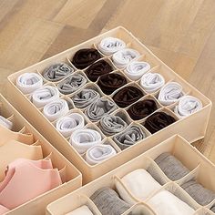 an open box filled with folded cloths on top of a wooden floor next to a pair of scissors