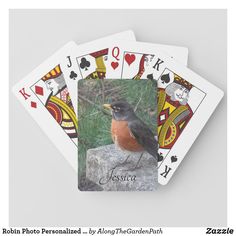 a robin perched on top of a rock playing cards with the name juscra