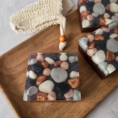 two soap bars sitting on top of a wooden tray next to a towel and beaded bag