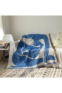 a blue and white blanket sitting on top of a bed next to a pillow in a room