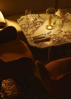 a marble table with two chairs and a vase on it, in a dimly lit room