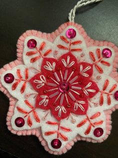 a red and white ornament hanging from a string on a black table top