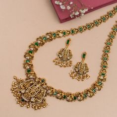 Description: Tarinika's temple design long necklace showcases an intricate Lord Balaji motif in the central medallion with his consorts Padmavati and Ambabai surrounded with floral, peacock, and elephant motifs. Polished with antique gold and studded with CZ and kempu stones for a grand, dramatic effect. Adorned with golden drop beads & pearl, this necklace is a bold statement piece perfect for your Wedding Wishlist. Details & Specification: Materials used: Brass Alloy with Antique Gold Plating Luxury Formal Temple Necklace With Meenakari, Luxury Ornate Meenakari Temple Necklace, Luxury Traditional Meenakari Temple Necklace, Luxury Ornate Temple Necklace With Intricate Design, Floral Peacock, Wedding Wishlist, Long Necklace Set, Lord Balaji, Temple Design