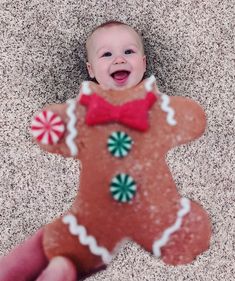 a baby in a red bow tie is holding a gingerbread man ornament