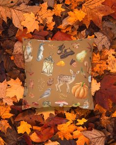 a square pillow with fall leaves surrounding it