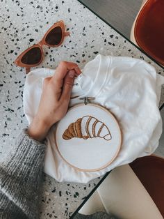 a person holding a white t - shirt with three croissants on it