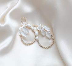 Introducing our stunning CELENA hoop earrings, perfect for weddings or any special occasion. Handcrafted with delicate white opal crystals and elegant freshwater pearls and flowers, these earrings add a touch of glamor and sophistication to any outfit. Make a statement with our gold floral hoops! - Handcrafted in my PA studio with genuine white opal Austrian crystals- Freshwater pearls- Polymer clay flowers and leaves- Yellow gold finish is pictured. Available in rose gold, yellow gold or rhodium (silver)- Earrings measure 2.5 inches x 1.5 inch- Handcrafted in the US.- Nickel free and hypoallergenic- PLEASE ALLOW APPROX 10 BUSINESS DAYS FOR COMPLETION BEFORE SHIPPING.This is an original design by © Treasures by Agnes Elegant Hoop Flower Earrings For Party, White Pearl Embellished Hoop Earrings For Wedding, Elegant Flower Hoop Earrings For Party, Glamorous Hoop Jewelry For Wedding, Glamorous Hoop Wedding Jewelry, Elegant Hoop Crystal Earrings, Wedding Hoop Earrings In Pearl White, Pearl White Wedding Hoop Earrings, Silver Hoop Bridal Earrings For Wedding