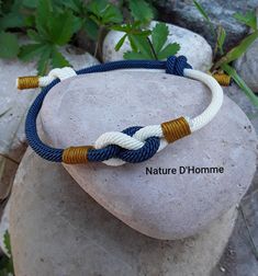 a white and blue rope bracelet on top of a rock