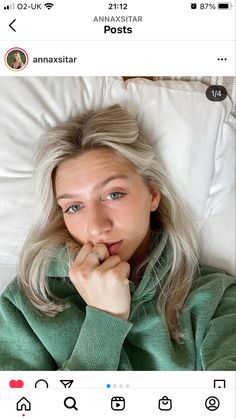 a woman laying in bed with her hand on her chin and looking at the camera