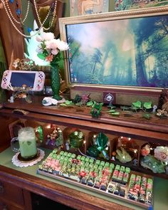 a table topped with lots of candy and candies next to a large painting on the wall