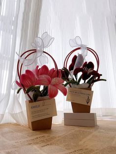 two vases with flowers in them sitting on a table